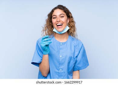 Young Blonde Woman Dentist Holding Tools Isolated On Blue Background With Surprise Facial Expression