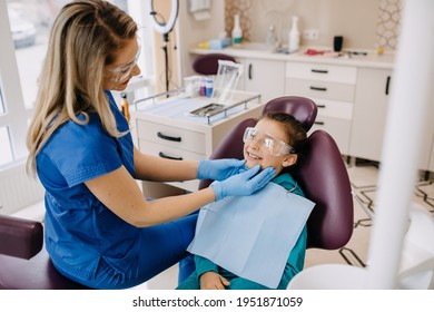 Young Blonde Woman Dentist With A Patient, Smiling. Child At A Dental Clinic At A Checkup.