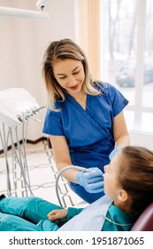 Young Blonde Woman Dentist With A Patient, Smiling. Child At A Dental Clinic At A Checkup.