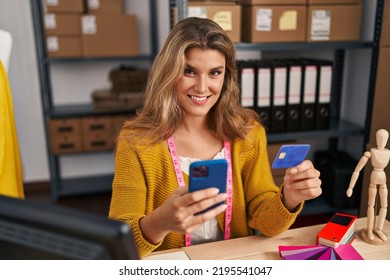 Young Blonde Woman Dressmaker Using Smartphone And Credit Card At Designer Studio