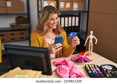 Young Blonde Woman Dressmaker Using Smartphone And Credit Card At Designer Studio