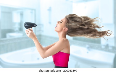 Young Blonde Woman Drying Her Long Hair With Electric Fan