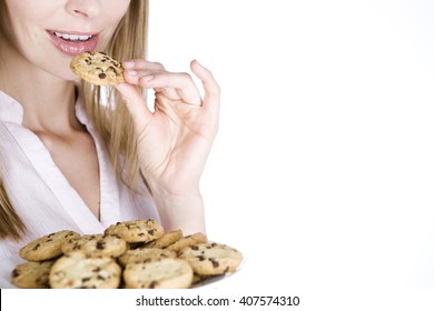 A young blonde woman eating a cookie
