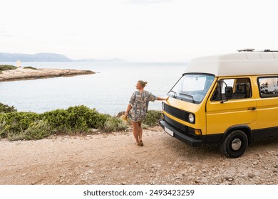 Young blonde woman enjoying the sea view in her yellow retro camper van parked on a dirt road above the sea on Korcula island, Croatia - Powered by Shutterstock