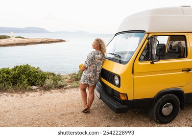 Young blonde woman enjoying the sea view in her yellow retro camper van parked on a dirt road above the sea on Korcula island, Croatia - Powered by Shutterstock