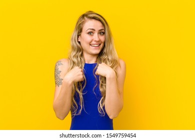 young blonde woman feeling happy, surprised and proud, pointing to self with an excited, amazed look against yellow wall - Shutterstock ID 1549759454