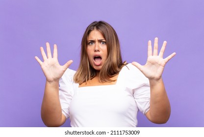 Young Blonde Woman Feeling Stupefied And Scared, Fearing Something Frightening, With Hands Open Up Front Saying Stay Away