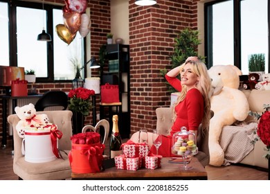 Young Blonde Woman Getting Luxury Valentines Day Gifts, Sitting In Living Room Filled With Expensive Present Boxes, Bear Soft Toy, Red Roses, Balloons. February 14 Girlfriend Romantic Greeting