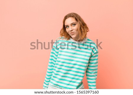 young blonde woman with a goofy, crazy, surprised expression, puffing cheeks, feeling stuffed, fat and full of food against flat color wall
