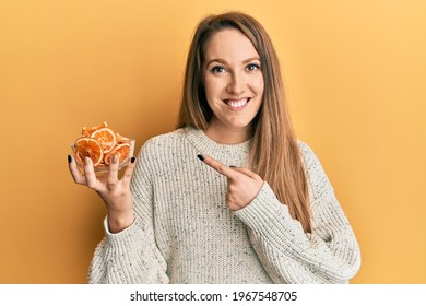 Young Blonde Woman Holding Bowl Of Dry Orange Smiling Happy Pointing With Hand And Finger 