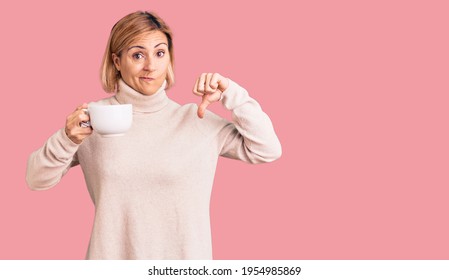 Young Blonde Woman Holding Coffee With Angry Face, Negative Sign Showing Dislike With Thumbs Down, Rejection Concept 