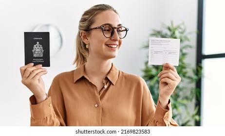 Young Blonde Woman Holding Covid Vaccination Record Card And Canada Passport At Waiting Room