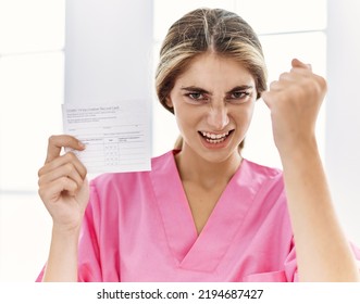 Young Blonde Woman Holding Covid Record Card Annoyed And Frustrated Shouting With Anger, Yelling Crazy With Anger And Hand Raised 