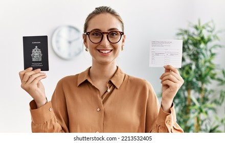 Young Blonde Woman Holding Covid Vaccination Record Card And Canada Passport At Waiting Room