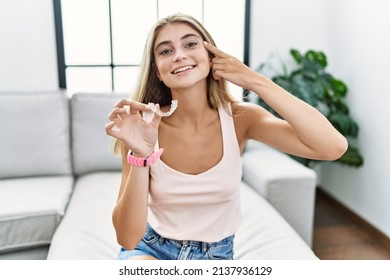 Young Blonde Woman Holding Invisible Aligner Orthodontic Smiling Pointing To Head With One Finger, Great Idea Or Thought, Good Memory 