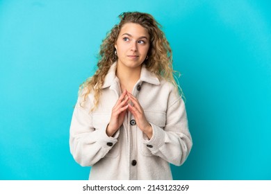 Young blonde woman isolated on blue background scheming something