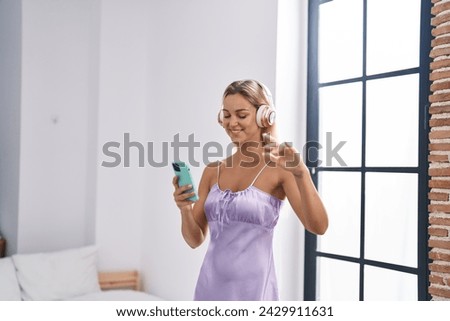 Young blonde woman listening to music and dancing at bedroom