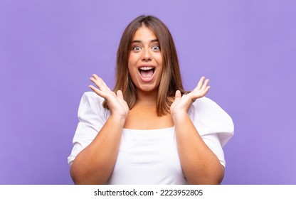 Young Blonde Woman Looking Happy And Excited, Shocked With An Unexpected Surprise With Both Hands Open Next To Face