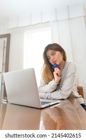 Young Blonde Woman Looking At Her Laptop Before Shopping Online With Credit Card. High Quality Photo