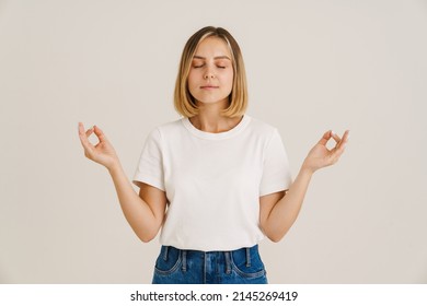 Young Blonde Woman Making Zen Gesture While Meditating Isolated Over White Background