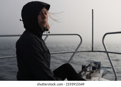 a young blonde woman in a membrane jacket is sitting on the cape of a yacht in the sea. Sea trip by boat. Fishing in the ocean - Shutterstock ID 2193915549