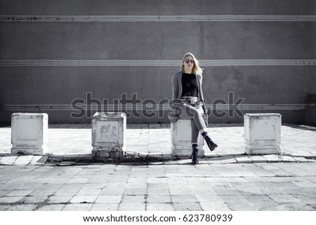 young blonde woman model sitting in front of office building
