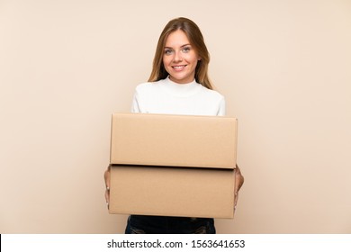 Young blonde woman over isolated background holding a box to move it to another site