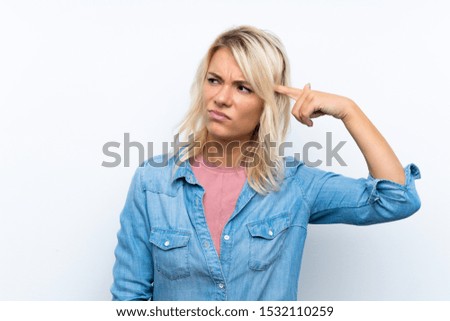 Young blonde woman over isolated white background making the gesture of madness putting finger on the head