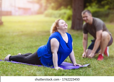 A young blonde woman of plus size performs an exercise on a sports ground with a trainer. Concept on healthy lifestyles - Shutterstock ID 1762223450