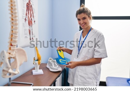 Young blonde woman podiatrist holding insole at clinic