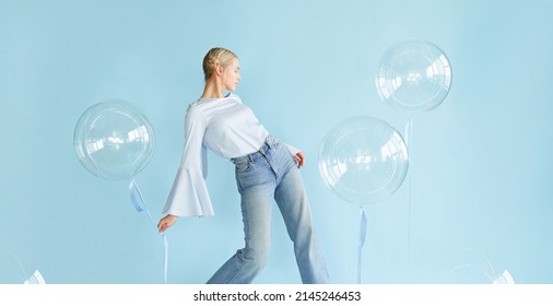 young blonde woman posing in studio with transparent balloons. Concept dreaming