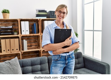 Young Blonde Woman Psychologist Holding Clipboard Standing At Clinic