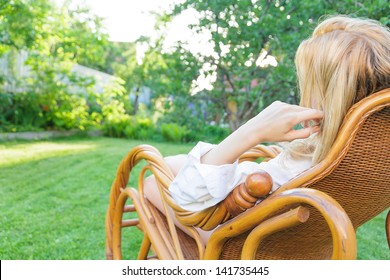 Young Blonde Woman Relax At Outdoor Sitting In A Rocking Chair