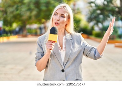 Young Blonde Woman Reporter Working Using Microphone At Park