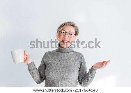 young blonde woman in round glasses and grey sweater