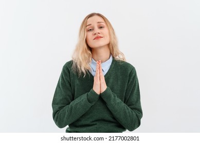 Young blonde woman showing clasped hands in pleading gesture, express gratitude, standing on white studio background. Religious lady praying, having hope for better future