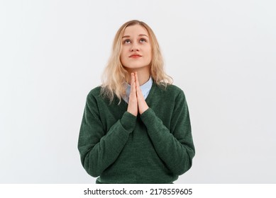Young blonde woman showing clasped hands in pleading gesture, express gratitude, standing on white studio background. Religious lady praying, having hope for better future