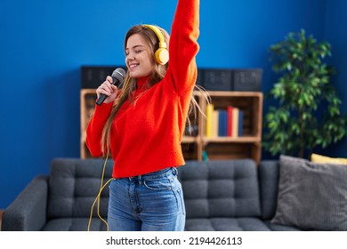 Young Blonde Woman Singing Song And Dancing At Home