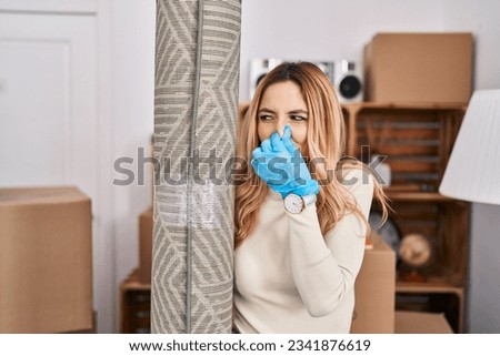 Young blonde woman smelling dirty carpet at new home