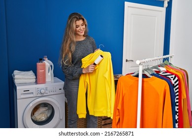 Young blonde woman smiling confident using clean hair pet roller at laundry room