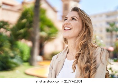Young blonde woman smiling confident looking to the sky at park