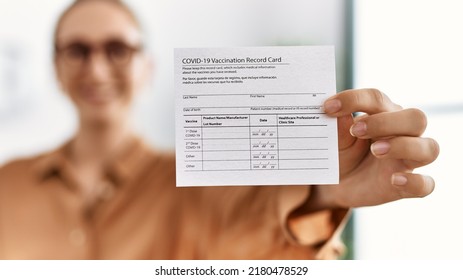 Young Blonde Woman Smiling Confident Holding Covid Vaccination Record Card At Waiting Room