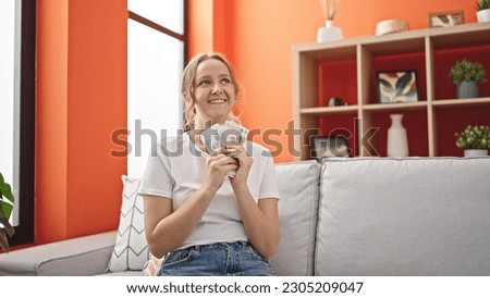 Young blonde woman smiling confident holding russia rubles banknotes at home