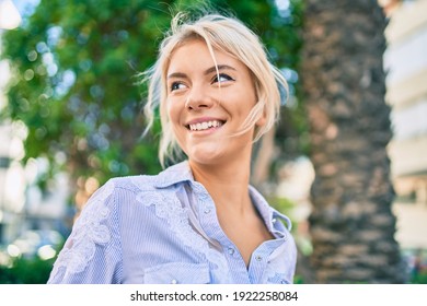 Young blonde woman smiling happy walking at the park.