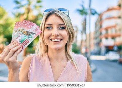 Young Blonde Woman Smiling Happy Holding New Zealand 100 Dollars Banknotes At The City.