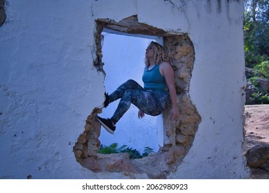 Young Blonde Woman In Sportswear, Doing Calisthenics Exercises In A Window Of A Dilapidated Building. Concept, Calisthenics, Fitness, Exercise, Curvy Girl.