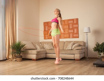 Young Blonde Woman In Sportswear Jumping With Rope At Home Cardio Workout