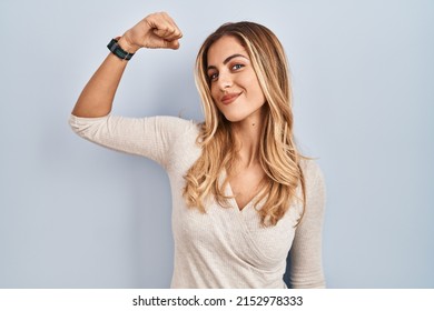 Young Blonde Woman Standing Over Isolated Background Strong Person Showing Arm Muscle, Confident And Proud Of Power 