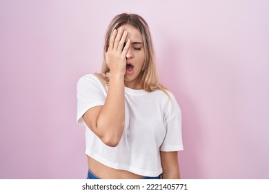 Young Blonde Woman Standing Over Pink Background Yawning Tired Covering Half Face, Eye And Mouth With Hand. Face Hurts In Pain. 