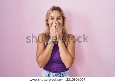 Young blonde woman standing over pink background laughing and embarrassed giggle covering mouth with hands, gossip and scandal concept  Сток-фото © 